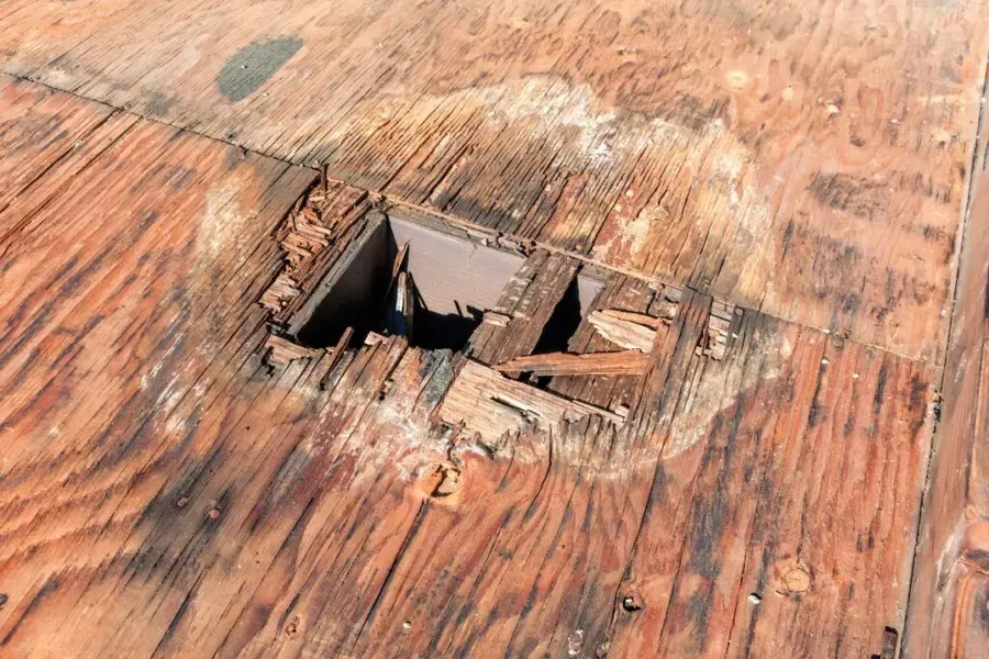 Water-damaged hardwood floor with boards cut out to reach the subfloor