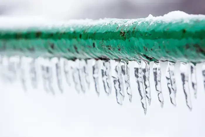 Icicles hanging from a frozen pipe during a hard freeze