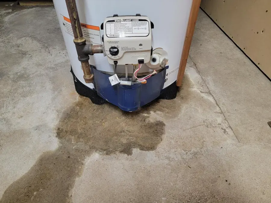 Gas water heater with water spread across the basement floor around it